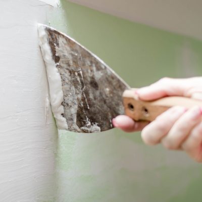 Woman plastering wall at house.